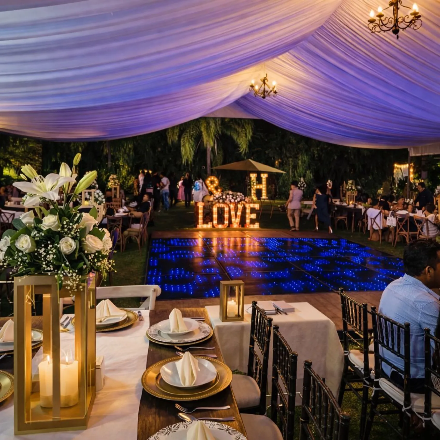 Recepción nocturna con pista iluminada y decoración de boda